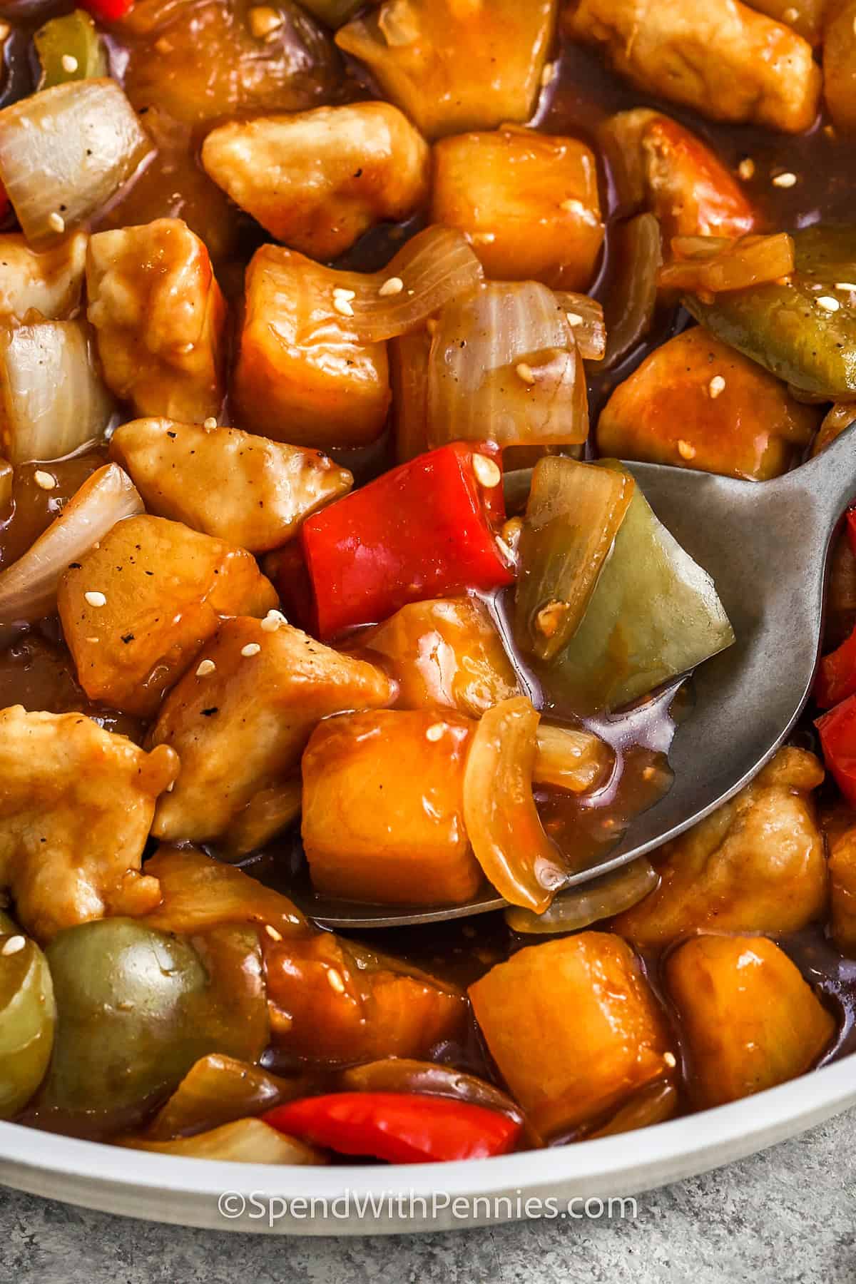 close up of Sweet and Sour Chicken in the pan with a spoon