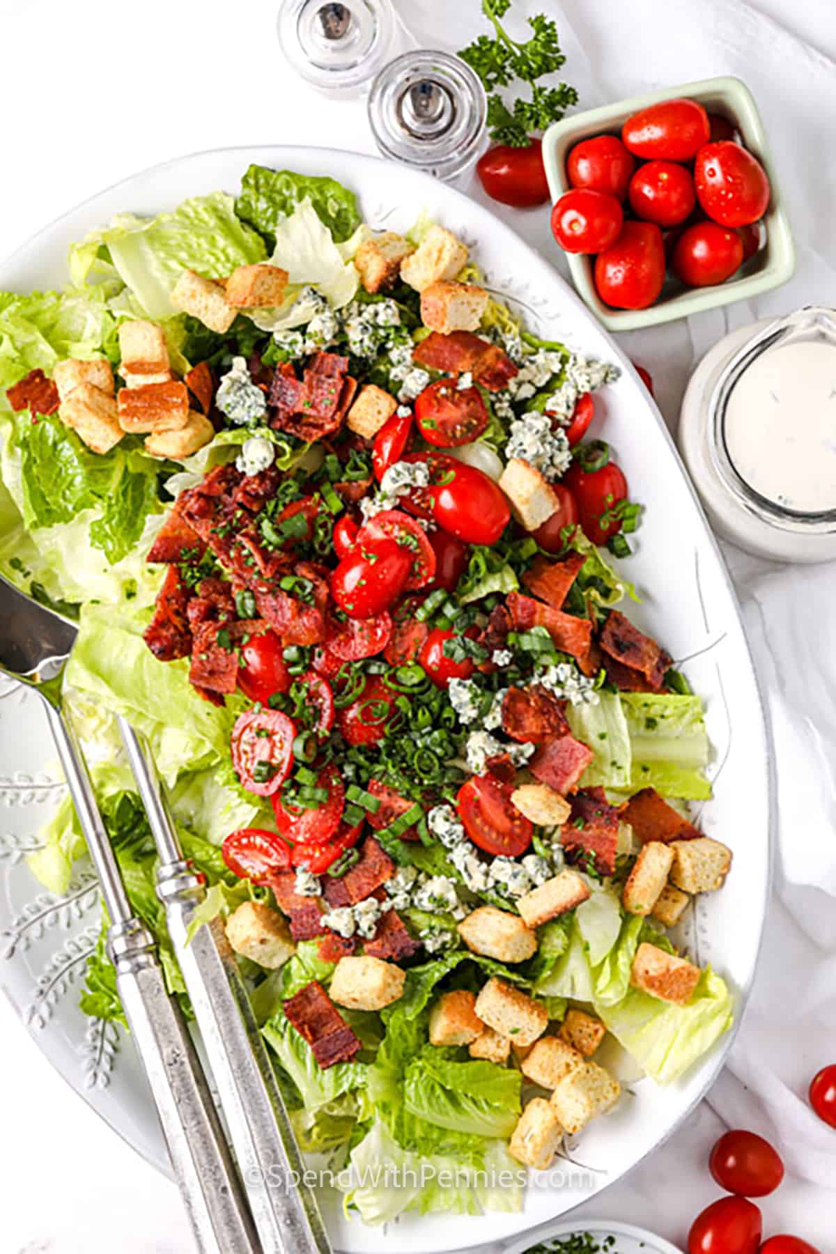 BLT salad is a crunchy, creamy, and delicious way to enjoy the flavors of your favorite sandwich in salad form. Romaine and iceberg lettuce pair with ripe tomatoes, crisp bacon, and your choice of cheese for a satisfying bite. The homemade dressing ties everything together with fresh herbs and zesty lemon. It's a perfect side or light dinner everyone will love. #spendwithpennies BLT Salad in a dish