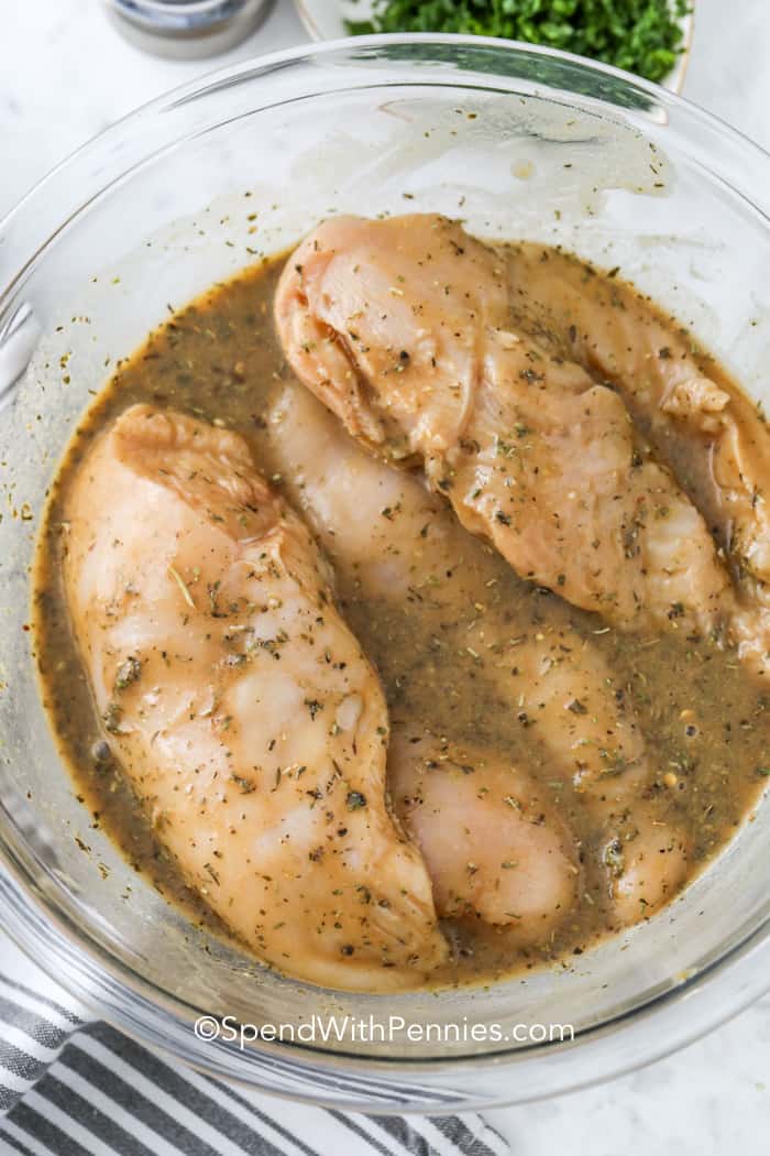 This quick and easy chicken marinade delivers the best flavor every time! It’s made with simple ingredients like soy sauce, Dijon mustard, and lemon juice to give grilled chicken breasts a juicy, savory kick. Great for a fast dinner or weekend BBQ, this recipe is a must-have for your mealtime rotation. Serve with fresh veggies or over a salad. #spendwithpennies Chicken Marinade and seasonings over chicken breasts in a bowl with parsley
