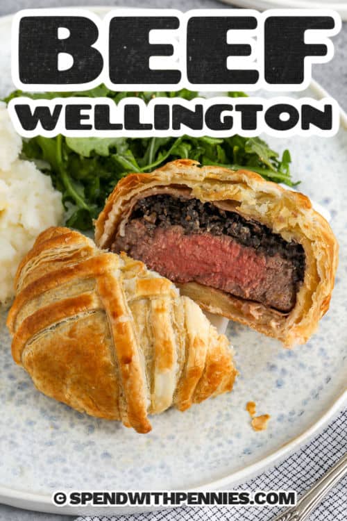 This Beef Wellington recipe wraps tender filet mignon in a layer of savory mushrooms, salty prosciutto, and golden, flaky puff pastry. Every bite is buttery, juicy, and full of rich flavor that feels like a restaurant meal made right at home. It's a beautiful way to impress guests or just treat yourself to something special without the fuss. Don't forget the mushroom duxelles—it makes all the difference! #spendwithpennies plated Beef Wellington with a title