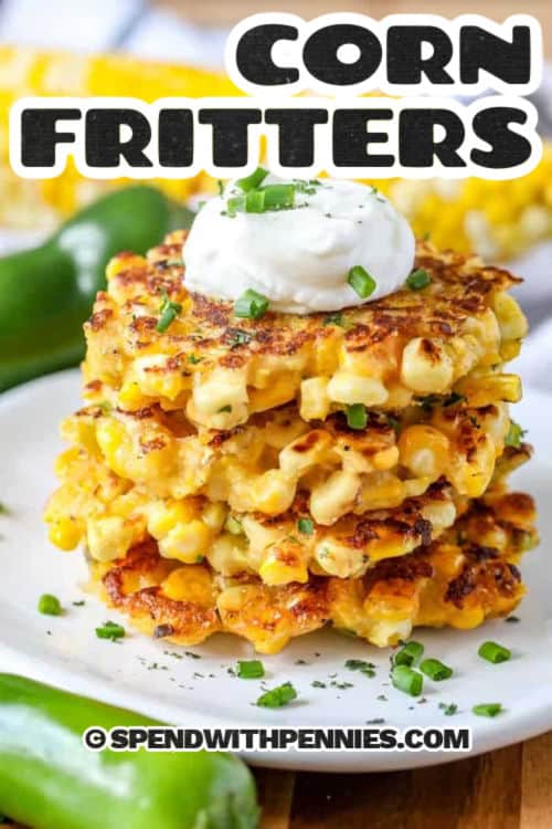 Corn fritters are a crispy fried side dish or appetizer that have layers of satisfying flavor in every bite. Corn meal and kernels are mixed up in a boldly seasoned batter with shredded cheese, jalapenos and smoked paprika, then fried to a golden brown. This easy recipe is quick to prep and cook. Make it richer with cream, or add extra nutrition with shredded zucchini or sweet potatoes. Serve with sour cream or hot sauce. It’s an easy way to add a pop of flavor to any meal. #spendwithpennies Corn Fritters on a plate with a title