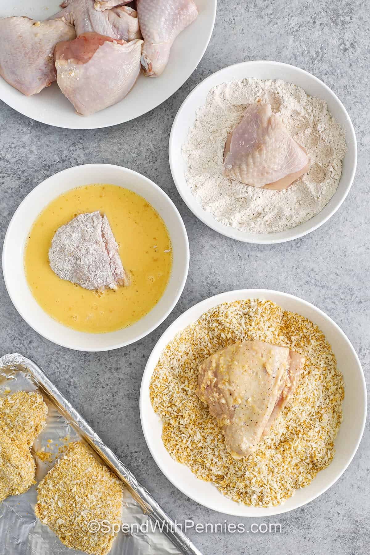 Oven fried chicken comes out crunchy and tender every time with this easy homemade coating mix! A seasoned blend of flour, garlic powder, and paprika adds flavor, while Panko and cornflakes make every bite extra crispy. Baked instead of fried, it's a lighter twist on a classic comfort food. Great for weeknight dinners or meal prep! #spendwithpennies process of coating Oven Fried Chicken with flour , egg wash and breadcrumbs