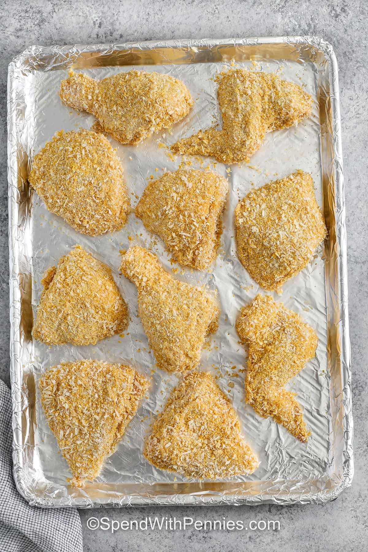 Oven fried chicken is a crispy and golden favorite that’s baked to perfection without the mess of oil! This easy recipe coats chicken in a flavorful mix of seasoned flour, egg wash, and a crunchy blend of Panko, cornflakes, and cornmeal. With a perfectly crisp crust and juicy inside, it’s a family favorite for dinner. Just bake until golden and delicious! #spendwithpennies breaded chicken on a sheet pan to make Oven Fried Chicken