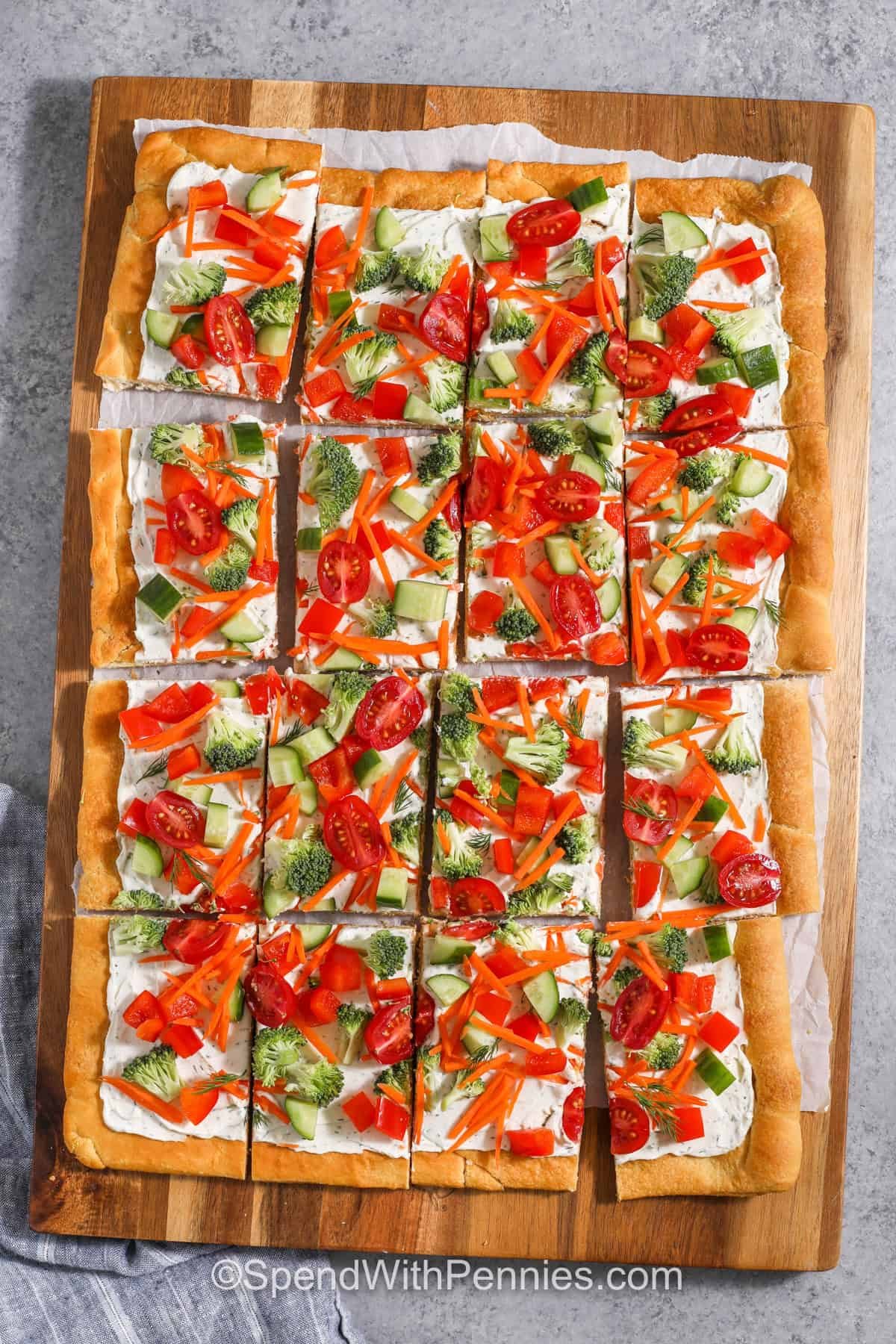 top view of a cut veggie pizza on a wooden serving tray
