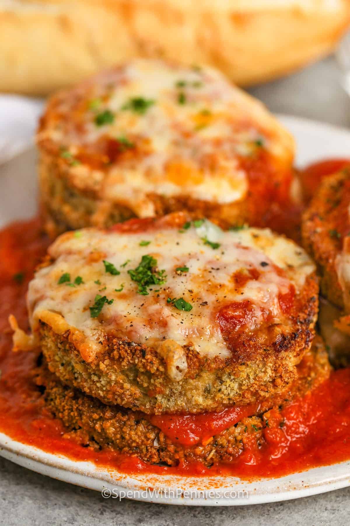 This air fryer eggplant parmesan recipe is an easy way to enjoy a fried favorite without the extra oil. The eggplant gets breaded, crisped up in the air fryer, and finished with marinara and melty mozzarella. It’s a great dish to cook when you want something cozy but lighter. Want a keto version? Just leave out the breadcrumbs. You can even swap in chicken for a protein-packed twist. #spendwithpennies plated crispy Air Fryer Eggplant Parmesan