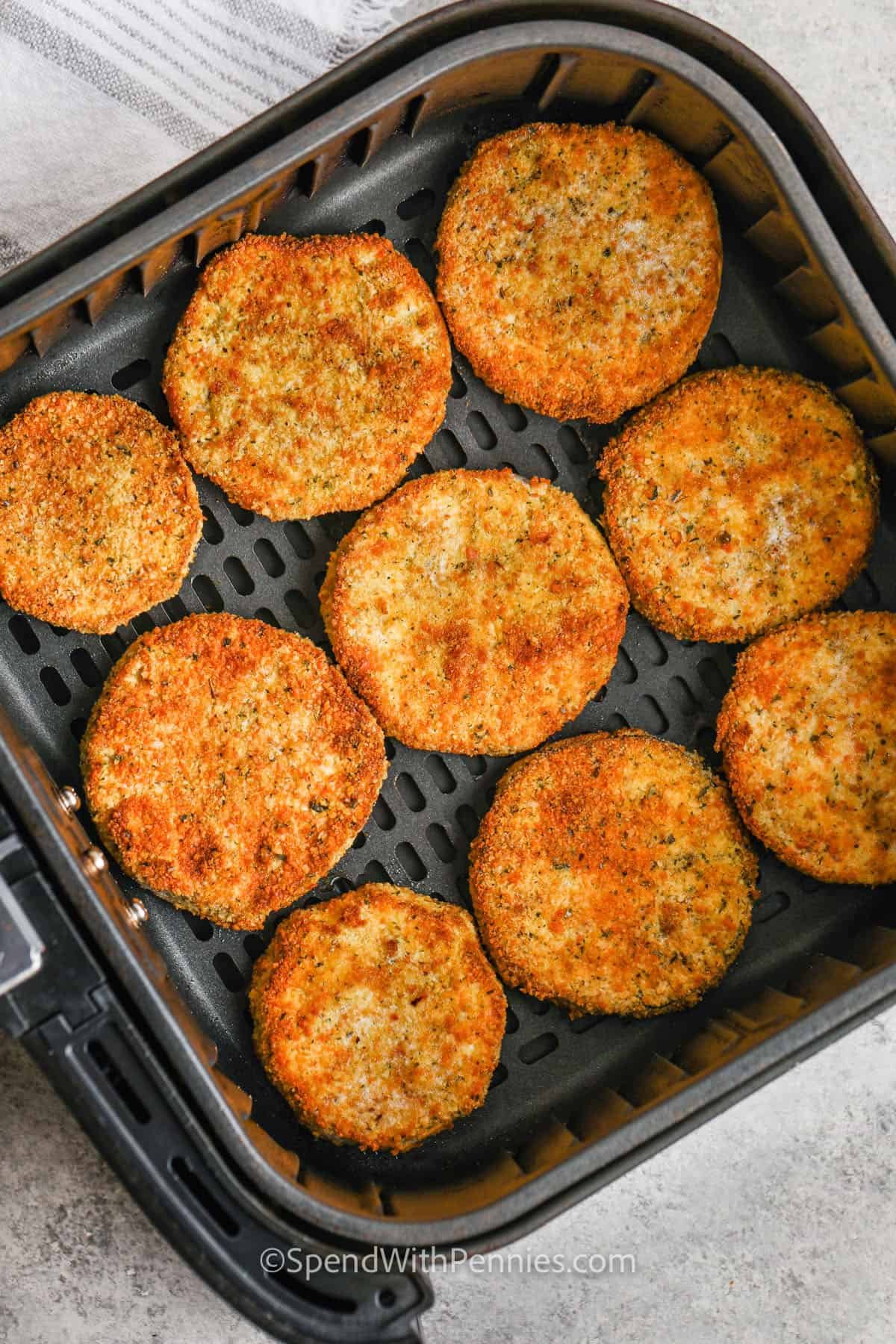 Air fryer eggplant parmesan is an easy recipe that brings all the crispy, cheesy goodness without deep frying. Breaded eggplant slices are air fried to perfection, then topped with marinara and melted cheese. It’s one of the best ways to make a lighter version of a classic. You can even swap in chicken cutlets for a twist. For a keto option, just skip the breadcrumbs and keep everything else the same. #spendwithpennies cooked Air Fryer Eggplant Parmesan in the fryer