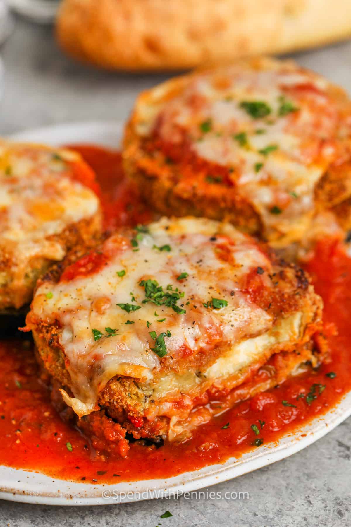 If you're looking for the best way to cook eggplant, this air fryer eggplant parmesan recipe is a must-try! Crispy breaded slices cook up perfectly in the air fryer, then get topped with sauce and melty cheese. It’s cozy, easy, and full of flavor. Swap eggplant for chicken for protein or skip the breadcrumbs to keep it keto-friendly. Either way, it’s a winner for busy weeknights. #spendwithpennies close up of Air Fryer Eggplant Parmesan on a plate