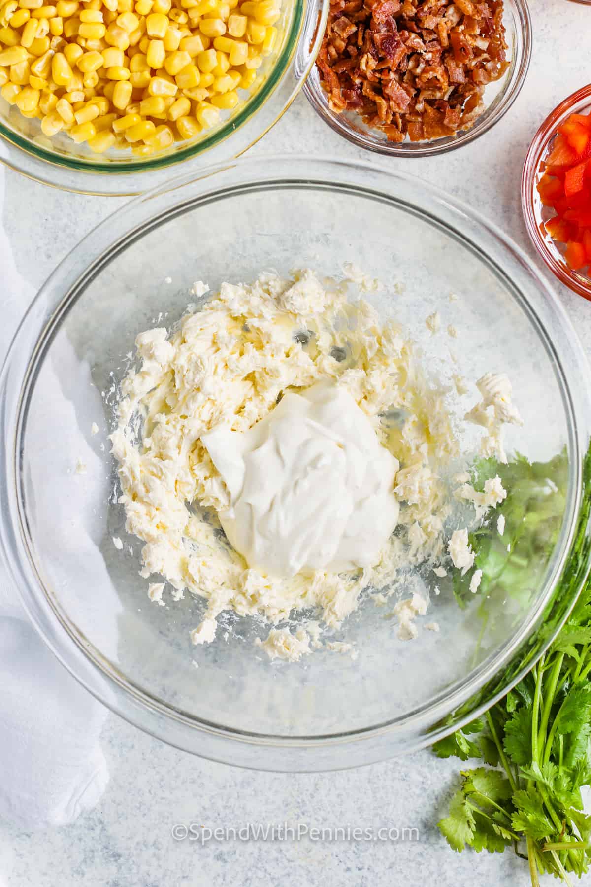 This corn dip recipe is full of creamy, cheesy flavor and just the right amount of spice. It’s loaded with corn, cream cheese, bacon, chiles, chili powder, and shredded cheddar, then baked until hot and melty. Inspired by street corn from Mexico, it’s perfect for serving with tortilla chips. Add beef for a heartier version or keep it simple for a tasty cold dip that works year-round. #spendwithpennies mixing ingredients to make sauce for Creamy Baked Corn Dip