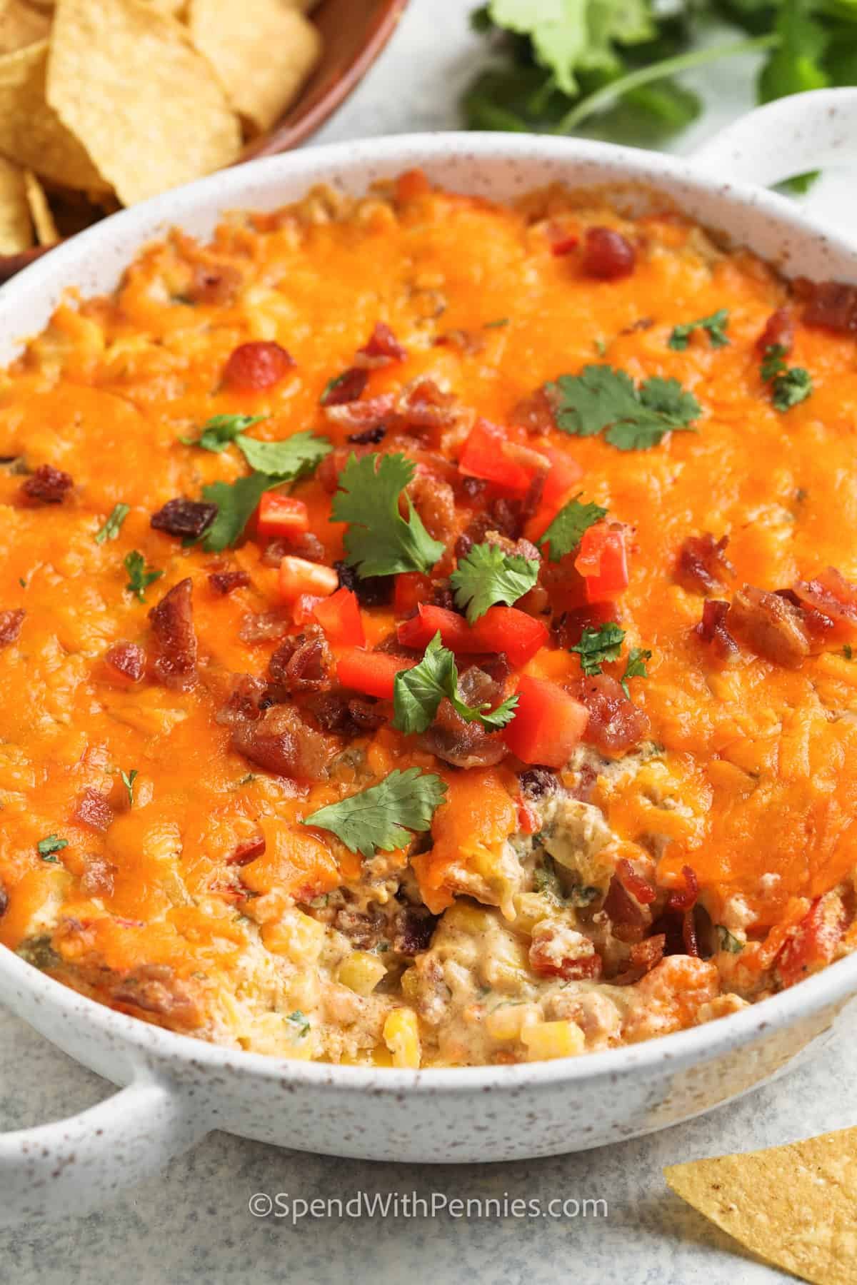 This creamy corn dip recipe is loaded with cheesy goodness and bold flavors inspired by Mexico. It’s made with sweet corn, cream cheese, chiles, and a hint of spice, baked until hot and bubbly. Serve it warm with sturdy chips or crackers for dipping. You can also make it cold and then reheat if you’re prepping ahead for a party. Add seasoned beef, black beans, or extra jalapeños for an bigger kick! #spendwithpennies close up of baked Creamy Baked Corn Dip