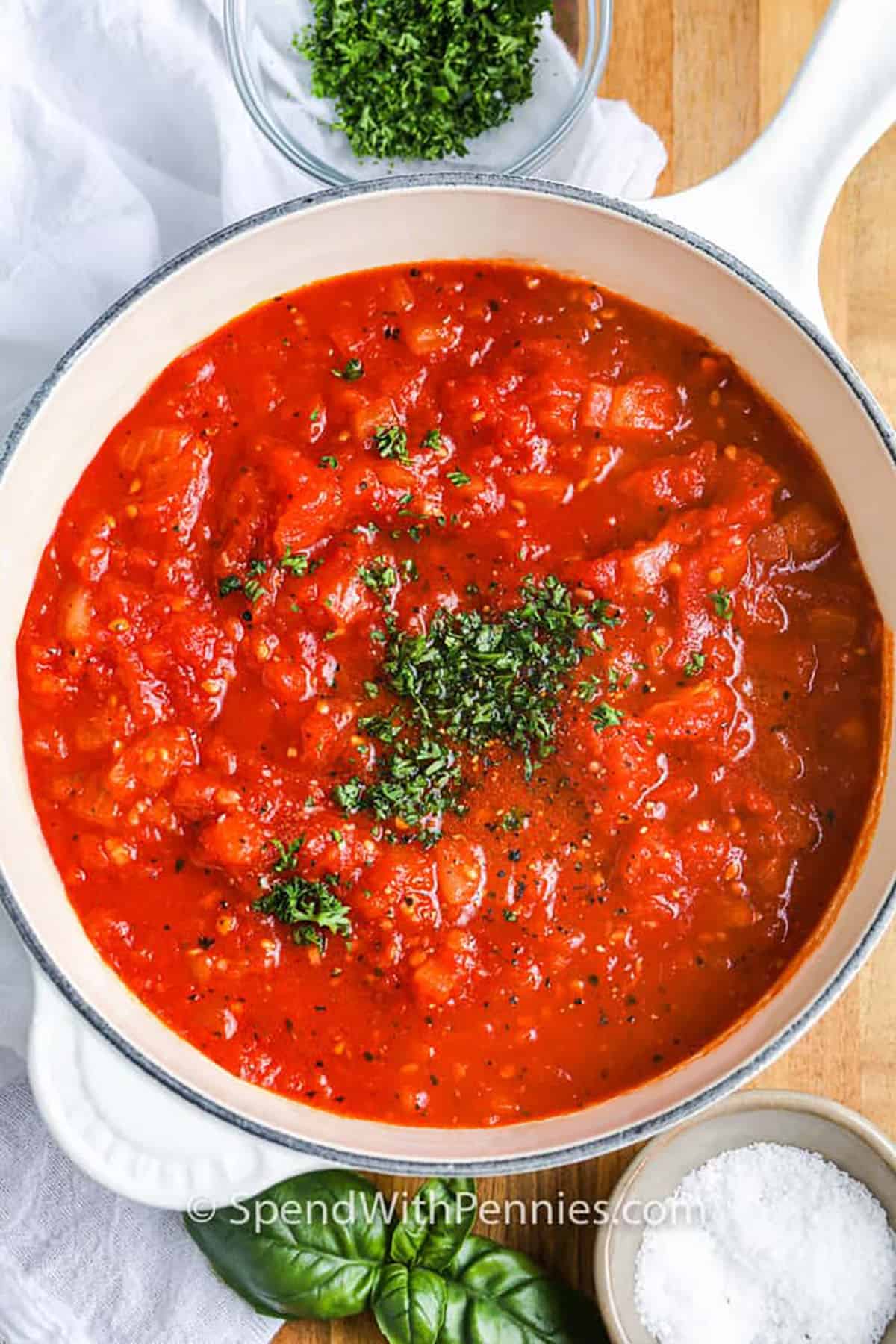 Tomato sauce made from canned whole tomatoes, garlic, onion, and herbs is a quick and flavorful classic recipe. Simmered until thick and rich, it’s versatile enough for spaghetti, meatballs, or chicken Parmesan. A touch of basil adds warmth, while parsley brightens it up at the end. You’ll never go back to jarred sauce after trying this easy homemade version. #spendwithpennies pot of Tomato Sauce with parsley